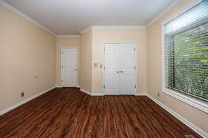 Unfurnished bedroom featuring wood finished floors, crown molding, and a closet