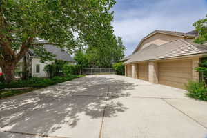 View of side of property featuring concrete driveway, brick siding, stucco siding, and a tiled roof