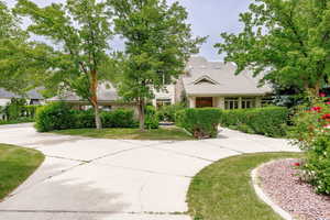 View of property hidden behind natural elements featuring a tiled roof and a front yard