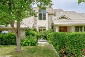 View of front of house with a tiled roof, a front yard, and brick siding