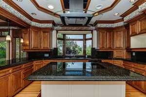 Kitchen with black electric cooktop, light wood finished floors, recessed lighting, brown cabinetry, and crown molding