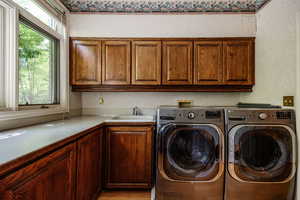 Washroom featuring cabinet space, washing machine and clothes dryer, and light wood-style flooring