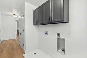 Laundry room with hookup for an electric dryer, washer hookup, cabinet space, and light wood-style flooring