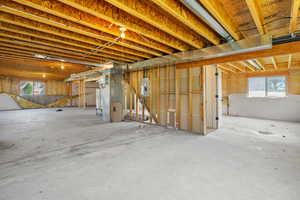 Below grade area with electric panel, plenty of natural light, heating unit, and gas water heater