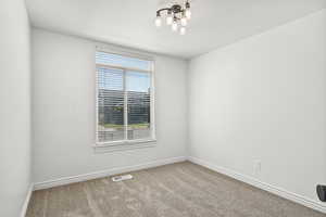 Carpeted spare room with baseboards and a chandelier