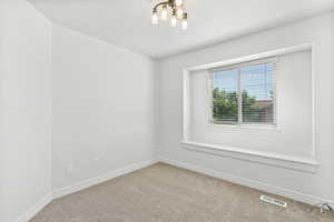 Unfurnished room featuring carpet floors and a chandelier
