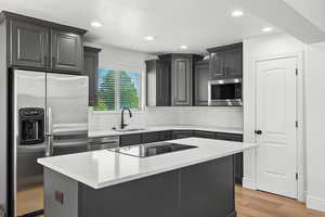 Kitchen featuring stainless steel appliances, tasteful backsplash, light wood-type flooring, recessed lighting, and a center island