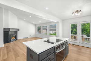 Kitchen with oven, black electric stovetop, light wood-type flooring, plenty of natural light, and recessed lighting