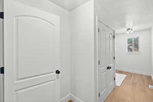 Hall featuring light wood-type flooring and a textured ceiling