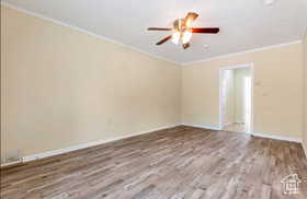 Spare room with wood finished floors, ornamental molding, and a ceiling fan