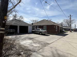 View of side of property featuring concrete driveway, brick siding, and a detached garage