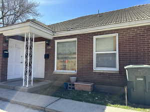 View of exterior entry with brick siding and a tile roof