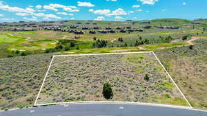 Aerial view of property and surrounding area featuring property parcel outlined, a golf club, and mountains