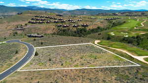 Aerial view of property's location featuring property parcel outlined, a mountain backdrop, and a golf club