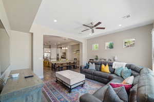 Living area featuring a ceiling fan, wood finished floors, arched walkways, recessed lighting, and a chandelier