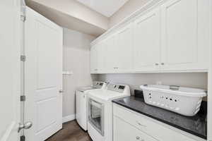 Laundry room with washer and clothes dryer, cabinet space, and dark wood finished floors