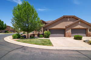 View of front of house with stucco siding, a garage, concrete driveway, stone siding, and a front lawn
