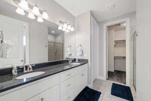 Bathroom featuring a stall shower, double vanity, a walk in closet, and tile patterned flooring
