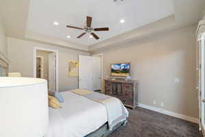Bedroom with a tray ceiling, dark colored carpet, recessed lighting, and ceiling fan