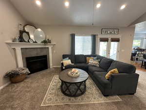 Carpeted living area with vaulted ceiling and a gas fireplace
