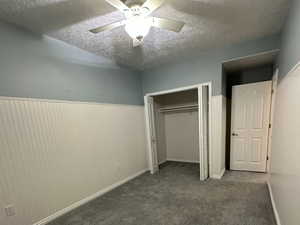 Carpeted bedroom with wainscotting and ceiling fan