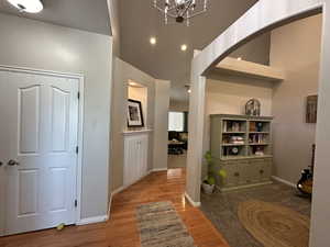 Entryway and sitting room featuring arched walkways, vaulted ceilings, and wood floors