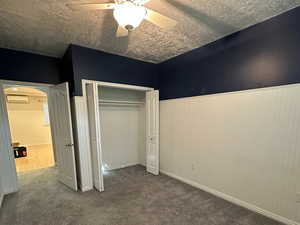 Carpeted bedroom with wainscotting and ceiling fan