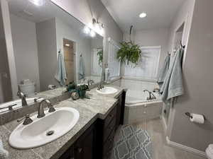 Bathroom featuring a bubbler tub, double vanity, and separate shower