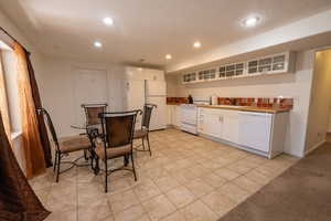 Kitchen featuring white appliances, recessed lighting, white cabinets, glass insert cabinets, and light tile patterned flooring