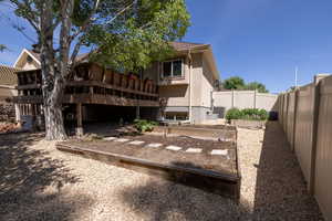 Rear view of property featuring a fenced backyard, a vegetable garden, stucco siding, and a wooden deck