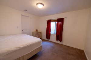 Bedroom featuring dark colored carpet and a textured ceiling