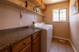 Laundry room with washer and dryer, light tile patterned floors, and cabinet space