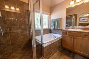 Full bathroom featuring vanity, a bath, a stall shower, and wood finished floors