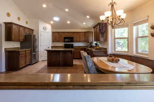 Kitchen with black microwave, freestanding refrigerator, a center island, a chandelier, and electric range oven