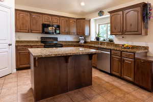 Kitchen featuring black appliances, a center island, light tile patterned floors, recessed lighting, and a breakfast bar