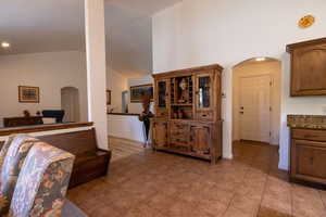 Living area with arched walkways, light tile patterned floors, and high vaulted ceiling