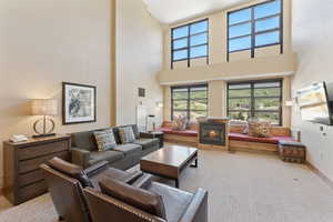 Carpeted living area with a towering ceiling and a glass covered fireplace