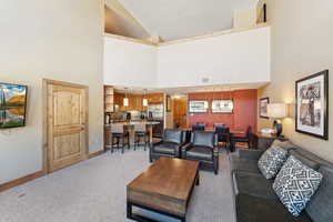 Living area featuring light colored carpet and high vaulted ceiling