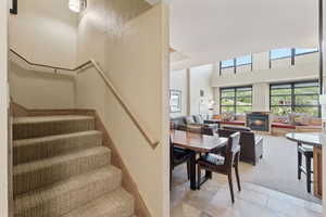 Staircase with a lit fireplace, a towering ceiling, carpet floors, and tile patterned floors