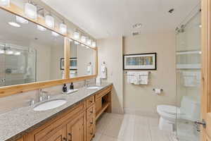 Full bathroom featuring double vanity, a shower stall, and tile patterned flooring