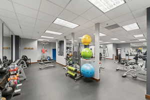Gym with baseboards and a paneled ceiling