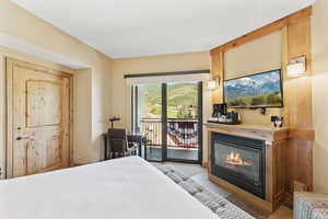 Bedroom featuring access to exterior and a glass covered fireplace
