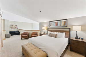 Bedroom featuring light carpet and vaulted ceiling
