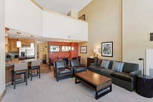 Living area featuring a towering ceiling and light carpet