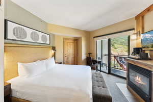 Bedroom with access to outside, a glass covered fireplace, and carpet floors