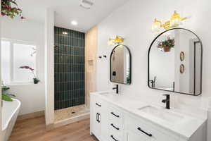 Bathroom featuring double vanity, a freestanding tub, custom tiled shower, and recessed lighting
