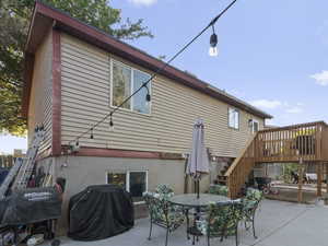 Back of property with stairway, a patio, outdoor dining area, and a deck