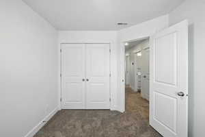 Unfurnished bedroom with dark carpet and a closet