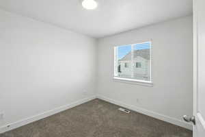 Spare room with dark colored carpet and baseboards