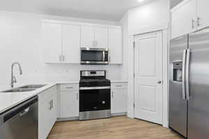 Kitchen featuring stainless steel appliances, light countertops, and white cabinetry